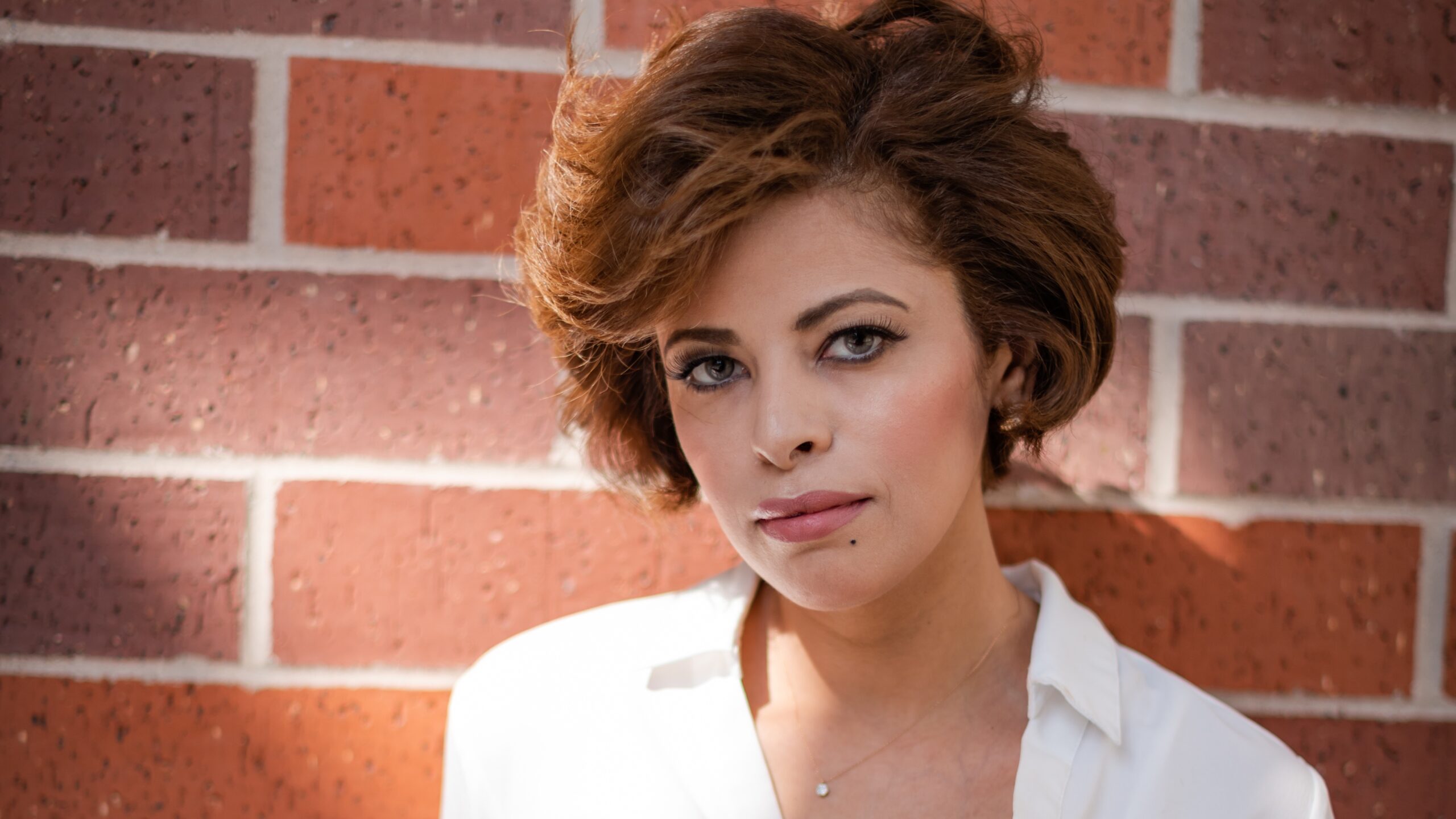 Exterior portrait of Ruby Alhajjar, with a brick wall background.